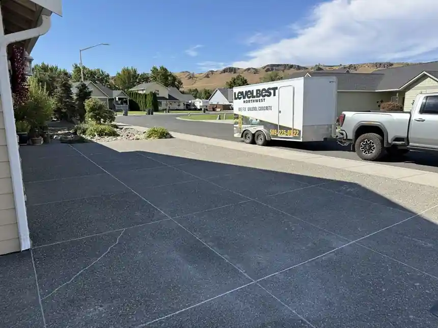 The Level Best Northwest trailer, lettered We Fix Unlevel Concrete, parked beside an exposed-aggregate driveway in Naches