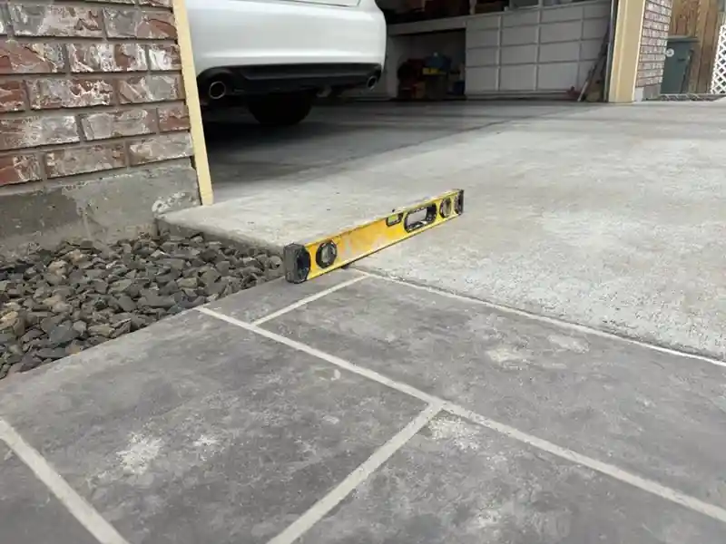 After: the same garage apron lifted flush with the patio, the level lying flat across the joint