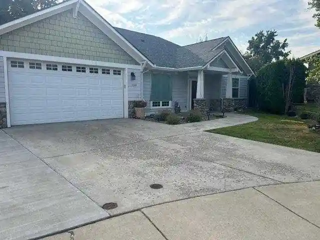 Before: a weathered garage driveway with stained, worn concrete in front of a two-car garage