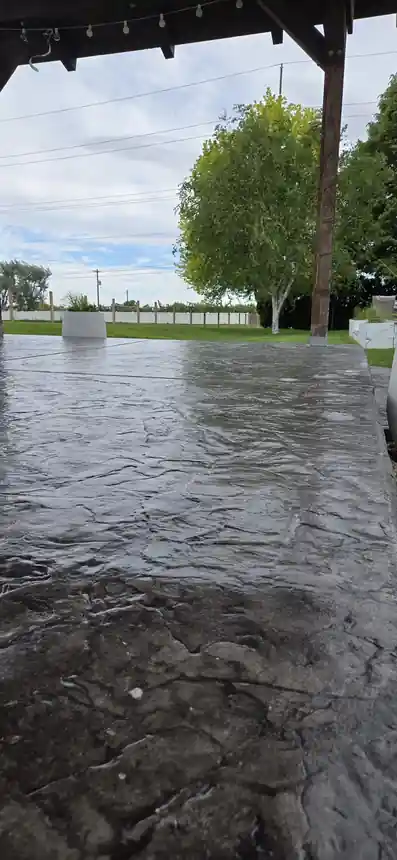 Stamped patio under a pergola with fresh sealer still glossy